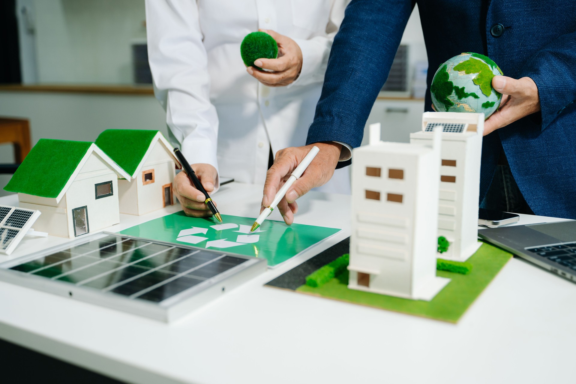 Engineers discuss solar panels and turbines in office, working on clean energy design, sustainable power